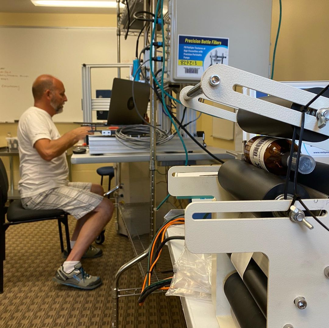 Pete sitting at and preparing to operate BEEpothecary bottle filling equipment.