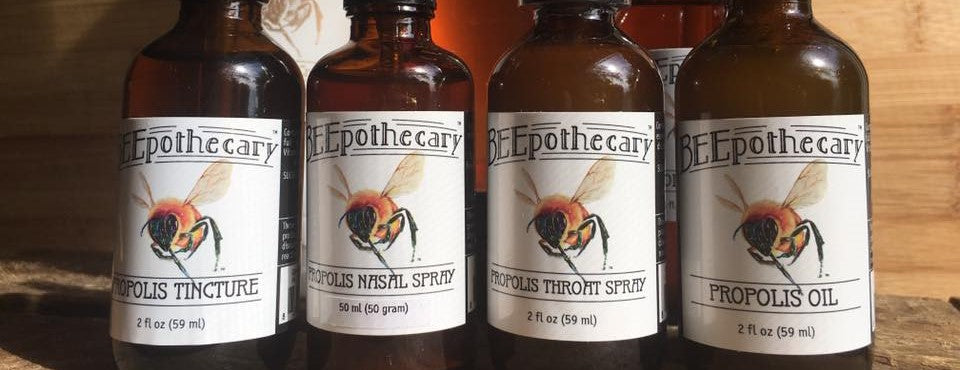 BEEpothecary propolis oil products in a row on a wooden table.