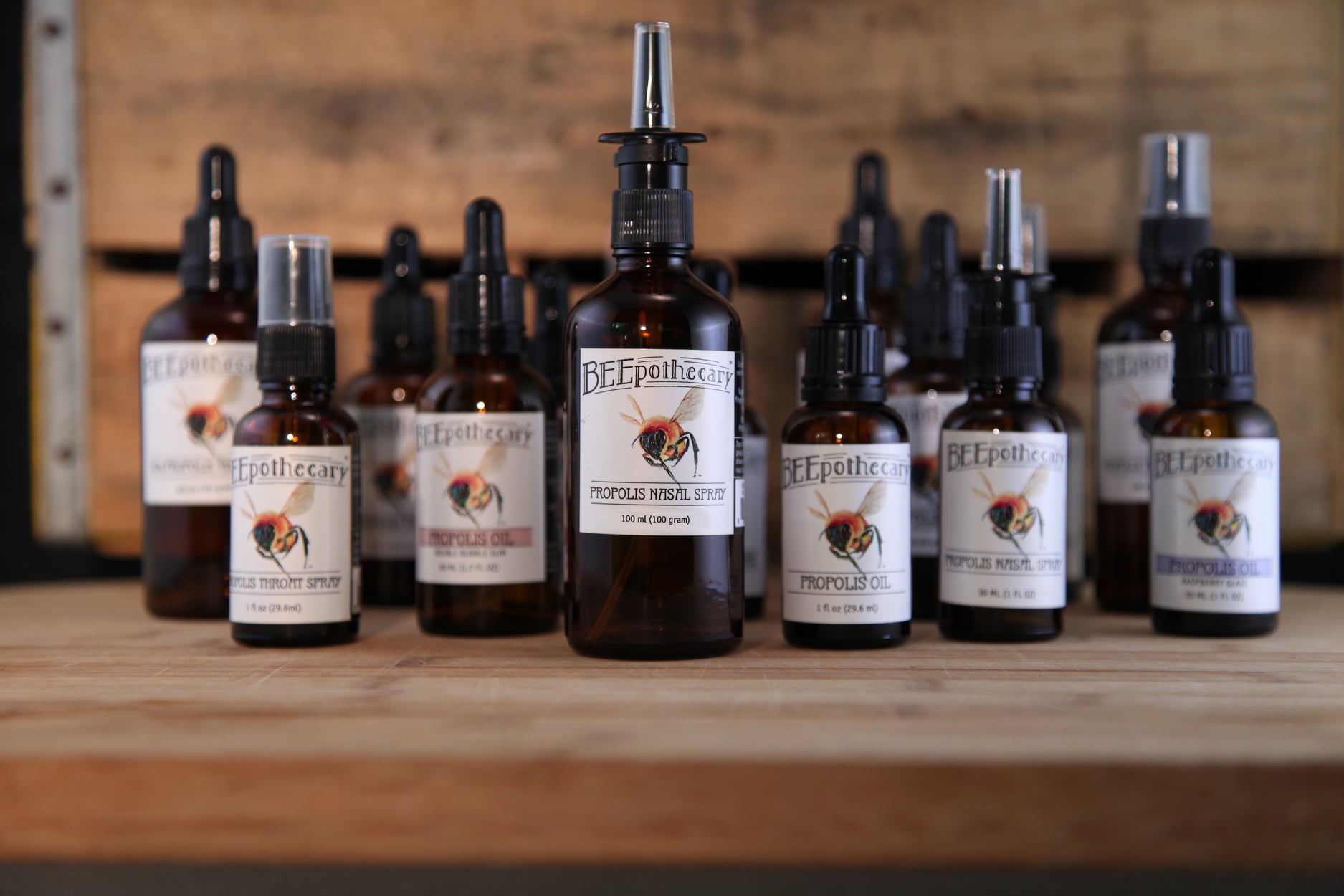 BEEpothecary propolis oil products lined up on a wooden table.
