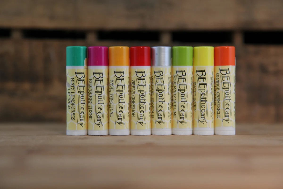 BEEpothecary honey bee lip balm flavors lined up in a row on a wooden table.